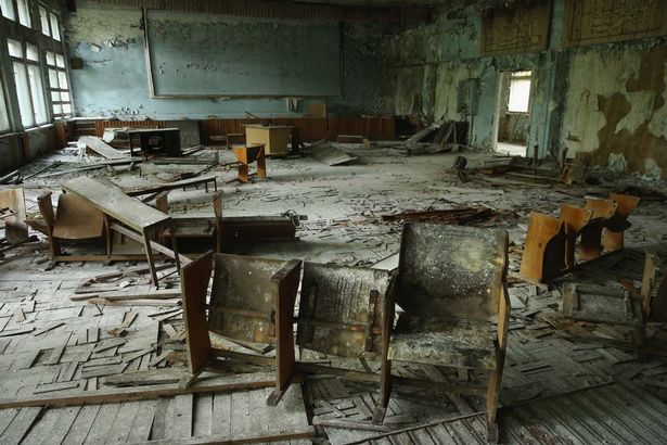 Pupils-chairs-stand-on-rotting-floorboards-in-an-auditorium-of-abandoned-School
